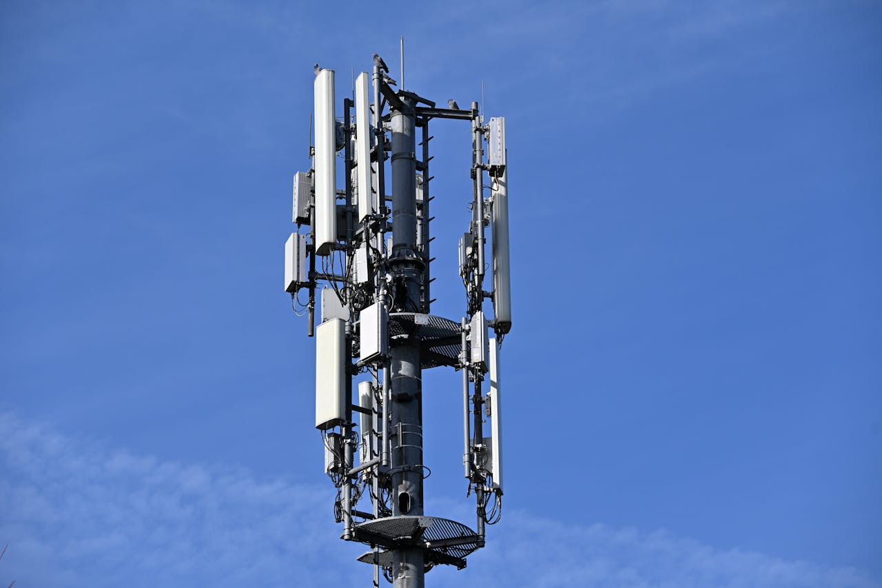 A modern cell tower with antennas against a clear blue sky, symbolizing connectivity.